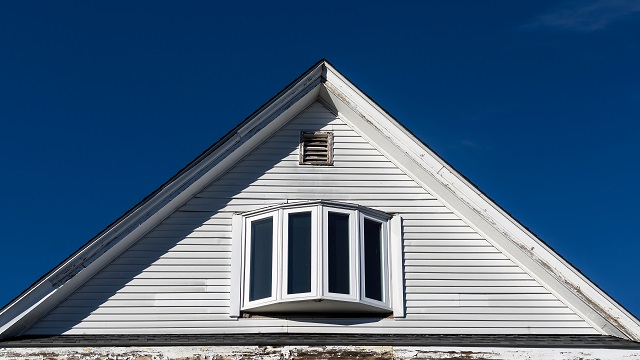 The top of a house with a window and gable vent 