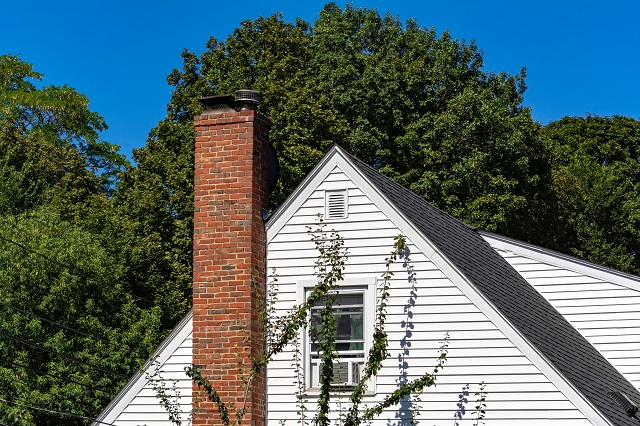 The top of a house with a chimney and gable vent