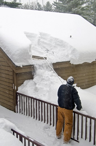 Person using a roof rake to remove snow from a roof