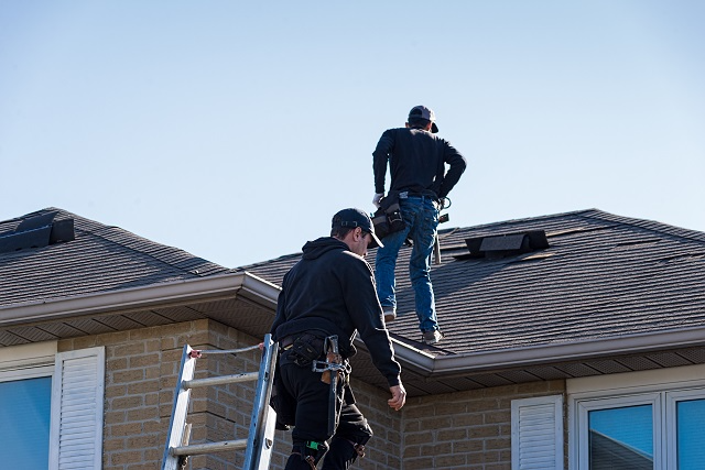 Roofers accessing a roof using an extension ladder