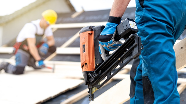 Roofing professional carrying a roofing nail gun