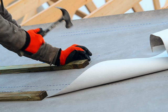 Roofer installing roof underlayment