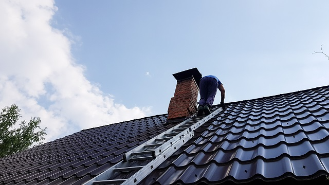 Roofing professional or homeowner climbing a ladder onto a roof