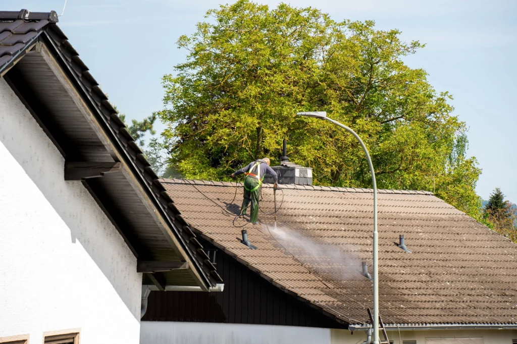 Person on a roof cleaning roof shingles